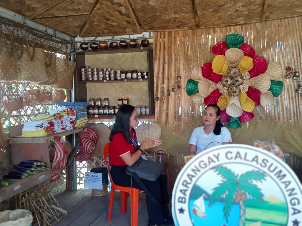 Negosyo Center–Polillo Business Counselor Mabelle V. Samas, evaluating one of the booths as one of the exhibitor.