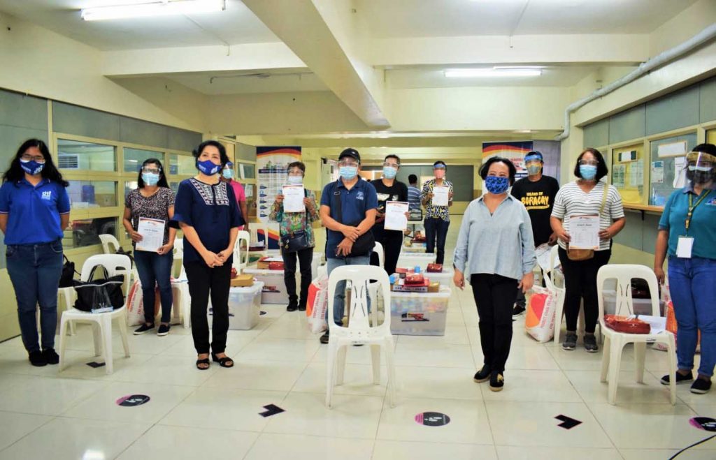 A group photo of DTI staff with the beneficiaries. They are all wearing masks and are standing far apart.